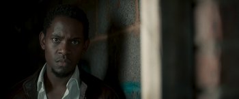 Movie still from “Yardie” (2018), directed by Idris Elba – A person wearing a suit and tie; Close Up shot, High angle