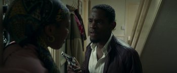 Movie still from “Yardie” (2018), directed by Idris Elba – A man holding a gun in front of a woman; Close Up shot, Over the shoulder angle