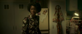 Movie still from “Yardie” (2018), directed by Idris Elba – A woman standing in front of an open door; Medium shot, Over the shoulder angle