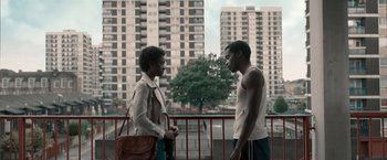 Movie still from “Yardie” (2018), directed by Idris Elba – A man and a woman standing next to each other on a bridge; Medium shot, Low angle
