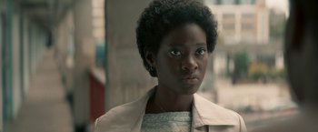 Movie still from “Yardie” (2018), directed by Idris Elba – A young woman with blue eyes is looking at the camera; Close Up shot, Over the shoulder angle