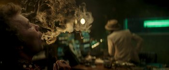 Movie still from “Yardie” (2018), directed by Idris Elba – Smoke billows out of a pipe in a dark room; Close Up shot, Over the shoulder angle