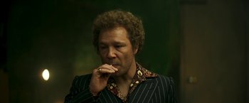 Movie still from “Yardie” (2018), directed by Idris Elba – A man in a striped jacket is eating something; Medium shot, Low angle