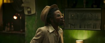 Movie still from “Yardie” (2018), directed by Idris Elba – A man in a hat and glasses is looking to his left; Close Up shot, Low angle