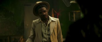 Movie still from “Yardie” (2018), directed by Idris Elba – A man wearing a hat and a jacket; Medium shot, Over the shoulder angle