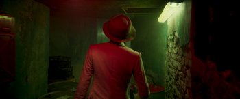 Movie still from “Yardie” (2018), directed by Idris Elba – A man wearing a red suit and a red hat; Medium shot, Low angle