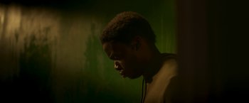 Movie still from “Yardie” (2018), directed by Idris Elba – A man with headphones on looking down at his face; Close Up shot, Low angle