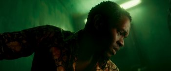 Movie still from “Yardie” (2018), directed by Idris Elba – A man's face in a green room; Close Up shot, Low angle