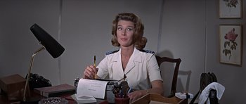 Movie still from “You Only Live Twice” (1967), directed by Lewis Gilbert – A woman sitting at a table writing on a piece of paper; Medium shot, Low angle
