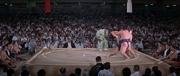 Movie still from “You Only Live Twice” (1967), directed by Lewis Gilbert – Two sumo wrestlers are in a ring while a crowd watches; Extreme Wide shot, High angle