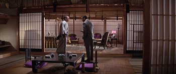 Movie still from “You Only Live Twice” (1967), directed by Lewis Gilbert – Two men standing in front of each other in front of a coffee table; Wide shot, Low angle