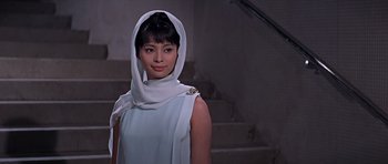 Movie still from “You Only Live Twice” (1967), directed by Lewis Gilbert – A woman wearing a head scarf standing in front of stairs; Close Up shot, Low angle