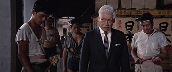 Movie still from “You Only Live Twice” (1967), directed by Lewis Gilbert – An older man in a suit and tie walking down a hallway; Medium shot, Low angle