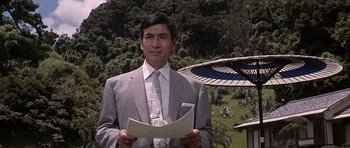 Movie still from “You Only Live Twice” (1967), directed by Lewis Gilbert – A man in a suit and tie holding papers; Medium shot, Low angle