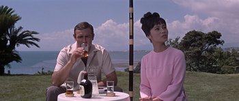 Movie still from “You Only Live Twice” (1967), directed by Lewis Gilbert – A man and a woman sitting at an outdoor table; Medium shot, Low angle