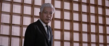 Movie still from “You Only Live Twice” (1967), directed by Lewis Gilbert – An older man in a black suit and white hair; Medium shot, Low angle