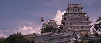 Movie still from “You Only Live Twice” (1967), directed by Lewis Gilbert – A helicopter flying over a castle with a sky background; Extreme Wide shot, Low angle