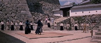 Movie still from “You Only Live Twice” (1967), directed by Lewis Gilbert – A group of people standing on a stone wall; Extreme Wide shot, High angle