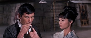 Movie still from “You Only Live Twice” (1967), directed by Lewis Gilbert – A man and a woman are smoking a cigarette together; Close Up shot, Over the shoulder angle