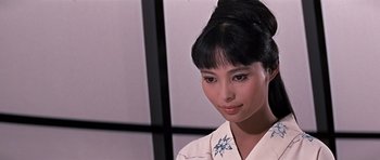 Movie still from “You Only Live Twice” (1967), directed by Lewis Gilbert – A woman in a white shirt and a black bun; Close Up shot, Over the shoulder angle