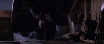 Movie still from “You Only Live Twice” (1967), directed by Lewis Gilbert – A person sitting on the ground in a dark room; Medium shot, High angle