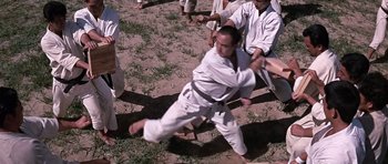 Movie still from “You Only Live Twice” (1967), directed by Lewis Gilbert – A man in a white shirt and black belt kicking a ball; Wide shot, Low angle