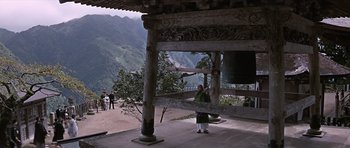 Movie still from “You Only Live Twice” (1967), directed by Lewis Gilbert – A person standing in front of a bell on the side of a hill; Extreme Wide shot, High angle