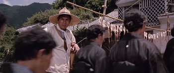 Movie still from “You Only Live Twice” (1967), directed by Lewis Gilbert – A man wearing a straw hat is standing next to other people; Medium shot, Low angle
