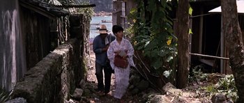 Movie still from “You Only Live Twice” (1967), directed by Lewis Gilbert – A man and a woman walking down a path near a body of water; Wide shot, High angle