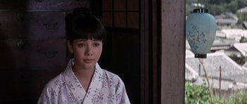 Movie still from “You Only Live Twice” (1967), directed by Lewis Gilbert – A young woman in a floral shirt looking at the camera; Close Up shot, High angle