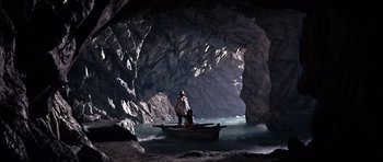 Movie still from “You Only Live Twice” (1967), directed by Lewis Gilbert – A man standing on a boat in the middle of a cave; Extreme Wide shot, High angle