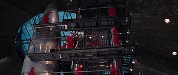 Movie still from “You Only Live Twice” (1967), directed by Lewis Gilbert – A group of people in red suits standing on a platform; Extreme Wide shot, Low angle