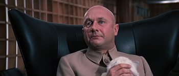 Movie still from “You Only Live Twice” (1967), directed by Lewis Gilbert – A bald man sitting in a chair holding a cat; Close Up shot, Low angle