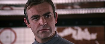 Movie still from “You Only Live Twice” (1967), directed by Lewis Gilbert – A person wearing a gray shirt; Close Up shot, Low angle