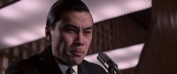 Movie still from “You Only Live Twice” (1967), directed by Lewis Gilbert – A person holding a microphone; Close Up shot, Low angle