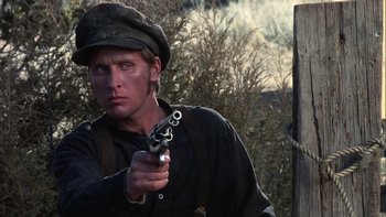 Movie still from “Young Guns” (1988), directed by Christopher Cain – A man holding a gun while standing next to a tree; Close Up shot, Low angle