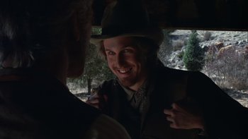 Movie still from “Young Guns” (1988), directed by Christopher Cain – A man wearing a hat is smiling at another man; Close Up shot, Over the shoulder angle
