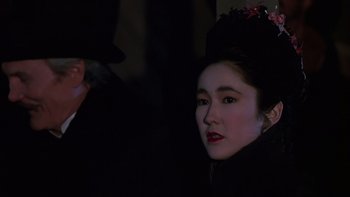 Movie still from “Young Guns” (1988), directed by Christopher Cain – A woman in a black outfit and a hat; Close Up shot, Over the shoulder angle