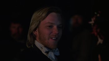 Movie still from “Young Guns” (1988), directed by Christopher Cain – A person wearing a suit and a bow tie; Close Up shot, Over the shoulder angle