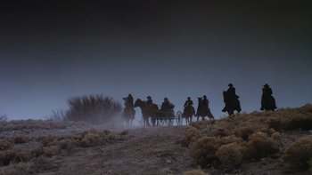 Movie still from “Young Guns” (1988), directed by Christopher Cain – A group of people riding on the back of a horse and carriage; Extreme Wide shot, Low angle