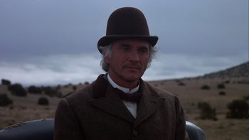 Movie still from “Young Guns” (1988), directed by Christopher Cain – A man in a brown suit and a brown hat; Close Up shot, Low angle