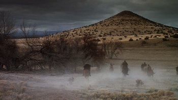 Movie still from “Young Guns” (1988), directed by Christopher Cain – A group of people riding horses through a field; Extreme Wide shot, High angle