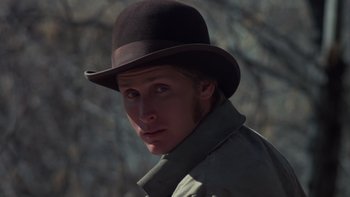 Movie still from “Young Guns” (1988), directed by Christopher Cain – A person wearing a hat with trees in the background; Close Up shot, Low angle