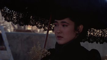 Movie still from “Young Guns” (1988), directed by Christopher Cain – A woman holding an open umbrella in the dark; Close Up shot, High angle