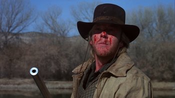 Movie still from “Young Guns” (1988), directed by Christopher Cain – A man in a cowboy hat with blood all over his face; Close Up shot, Low angle