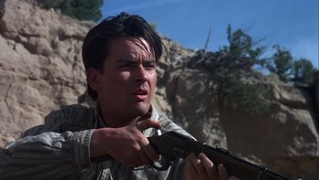 Movie still from “Young Guns” (1988), directed by Christopher Cain – A man holding a gun and pointing to the ground; Close Up shot, Low angle
