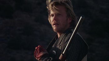 Movie still from “Young Guns” (1988), directed by Christopher Cain – A man holding a baseball bat while standing in a field; Close Up shot, Low angle