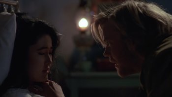 Movie still from “Young Guns” (1988), directed by Christopher Cain – A man and a woman face to face in a dark room; Close Up shot, Over the shoulder angle