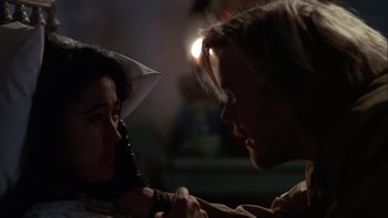 Movie still from “Young Guns” (1988), directed by Christopher Cain – A man and a woman face each other in the dark; Close Up shot, Over the shoulder angle