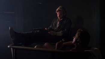 Movie still from “Young Guns” (1988), directed by Christopher Cain – A man and a woman sitting on a bed; Medium shot, Over the shoulder angle